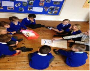 Figure 3 shows a picture of children and their teacher sitting in a circle on the floor during an exercise using the prompt sheet.